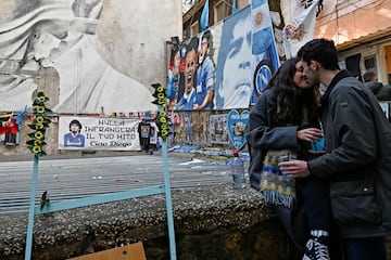 Una pareja se besa delante de los murales de Diego Maradona en Quartieri Spagnoli, en el centro de Nápoles.