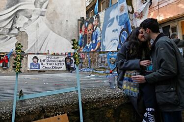 Una pareja se besa delante de los murales de Diego Maradona en Quartieri Spagnoli, en el centro de Nápoles.