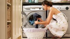 Woman loading washing machine in kitchen