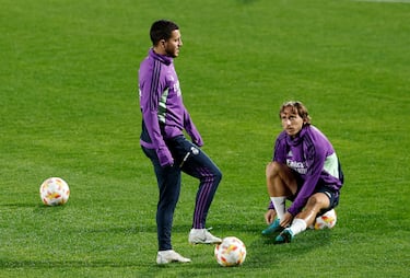 Eden Hazard controla un balón junto a Luka Modric que se ata las botas.