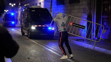 A protester throws a crowd control barrier towards members of the Catalan regional police force Mossos d'Esquadra during a demonstration against new coronavirus restrictions in Barcelona on October 30, 2020. - One by one, Spain's regions have announced regional border closures in the hope of avoiding a new lockdown like in France. The central government unveiled a state of emergency to give regional authorities the tools to impose curfews and close their borders to anyone moving without just cause. (Photo by Josep LAGO / AFP)