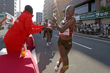 La ganadora olímpica de maratón Peres Jepchirchir recibe su bebida durante la carrera. 