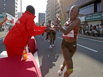 La ganadora olímpica de maratón Peres Jepchirchir recibe su bebida durante la carrera. 