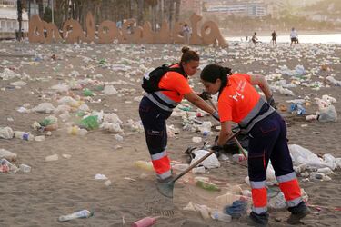 Miembros del servicio de limpieza municipal de Málaga recogen restos de basura en la playa de La Malagueta.