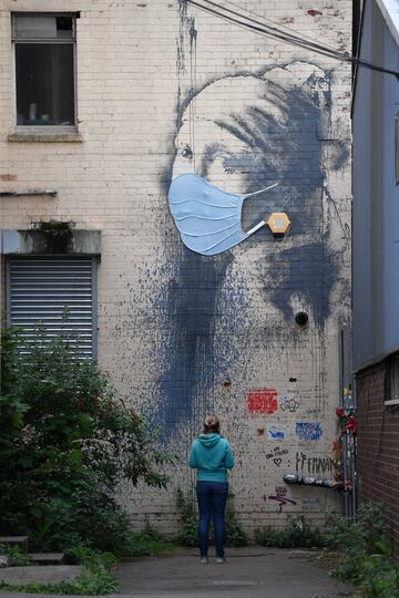 BRISTOL, ENGLAND - APRIL 27: A member of the public pauses to view the graffiti artwork by Banksy named 'Girl with a Pierced Eardrum' is seen with a protective face mask at Hannover Place on April 27, 2020 in Bristol, England