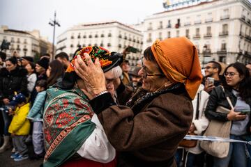 Dos mujeres se colocan el pañuelo de su traje regional para recibir al rebaño trashumante a su paso por la Puerta del Sol.