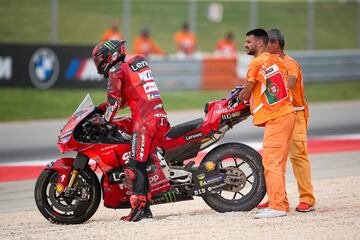 Francesco Bagnaia observa el estado de su moto sujetada por dos operarios de carrera. El piloto italiano no pudo continuar su carrera en Portimao.