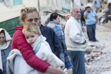 ITA04 AMATRICE (ITALIA) 24/08/2016.- Una mujer abraza a su hijo en medio de los escombros en Amatrice, en el centro de Italia, hoy, 24 de agosto de 2016. Al menos 19 personas han fallecido y hay decenas de heridos tras el terremoto de 6 grados en la escala Richter que ha sacudido el centro de Italia esta madrugada, según informó la televisión pública RAI. EFE/Massimo Percossi