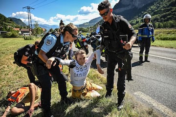 French gendarmes remove environmental protestors from the race route as their protest action temporarily immobilized the pack of riders during the 10th stage of the 109th edition of the Tour de France cycling race, 148,1 km between Morzine and Megeve, in the French Alps, on July 12, 2022. 