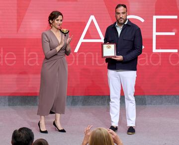 La presidenta de la Comunidad de Madrid, Isabel Díaz Ayuso (i), entrega una placa de honor de la Orden del Dos de Mayo a la Denominación de Origen Protegida Aceites de Madrid.