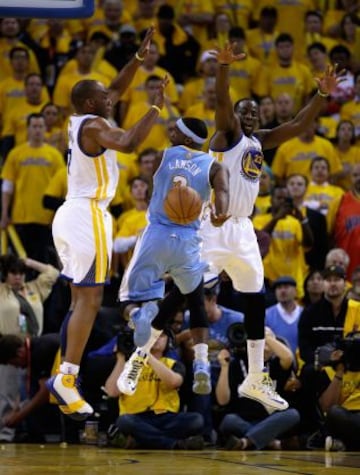 Ty Lawson de los Nuggets de Denver realiza un pase de espaldas mientras es custodiado por Carl Landry y Draymond de los Golden State Warriors en el tercer partido de los cuartos de final de la Conferencia Oeste de los Playoffs de la NBA en 2013.