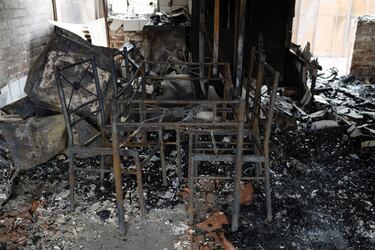 Varios restos de muebles quemados se encuentran entre los escombros de una casa quemada.