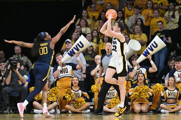 Caitlin Clark, base Iowa State, lanza a una pierna ante Jayla Hemingay, de West Virginia Mountaineers.