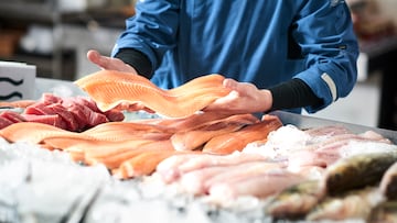 A young male shop assistant in a fishshop saling fresh fish