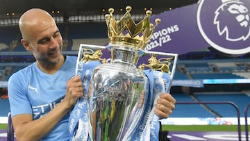 TOPSHOT - Manchester City's Spanish manager Pep Guardiola celebrates with the Premier league trophy on the pitch after the English Premier League football match between Manchester City and Aston Villa at the Etihad Stadium in Manchester, north west England, on May 22, 2022. - Manchester City won the Premier League for the fourth time in five seasons after a pulsating title race reached a dramatic conclusion as the champions staged an incredible comeback from two goals down to beat Aston Villa 3-2 on Sunday. (Photo by Oli SCARFF / AFP) / RESTRICTED TO EDITORIAL USE. No use with unauthorized audio, video, data, fixture lists, club/league logos or 'live' services. Online in-match use limited to 120 images. An additional 40 images may be used in extra time. No video emulation. Social media in-match use limited to 120 images. An additional 40 images may be used in extra time. No use in betting publications, games or single club/league/player publications. /