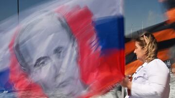 A woman carries a flag with a portrait of Russian President Vladimir Putin during celebrations of International Workers' Day in Omsk, Russia May 1, 2023. REUTERS/Alexey Malgavko