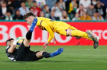 El portero del Elche, Edgar Badía, se queda con el balón mientras Gavi se queda suspendido en el aire.