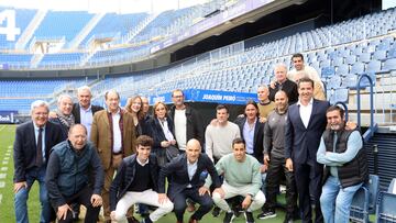 Exjugadores del M¨¢laga posan con la familia de Peir¨® en el banquillo que lleva su nombre.