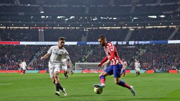 El delantero del Atlético, Yannick Carrasco, avanza con el balón ante el defensa del Sevilla, Gonzálo Montiel.