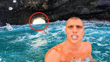 El surfista Koa Smith mirando a cámara con el mar revuelto a sus espaldas, acompañado de un agujero en un acantilado al fondo, rodeado con un círculo rojo.