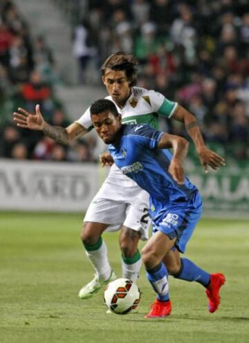 El centrocampista colombiano del Getafe, Fredy Hinestroza, intenta controlar el balón ante el defensa uruguayo del Elche, Damián Nicolás Suárez, durante el encuentro correspondiente a la jornada 30 de primera división.