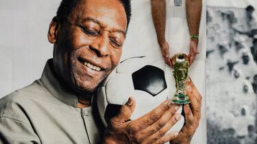 FILE PHOTO: Soccer Football - FIFA World Cup Qatar 2022 - Group G - Cameroon v Brazil - Lusail Stadium, Lusail, Qatar - December 2, 2022 Brazil fan holds a replica World Cup trophy in front of a banner of former Brazil player Pele inside the stadium before the match REUTERS/Benoit Tessier/File photo