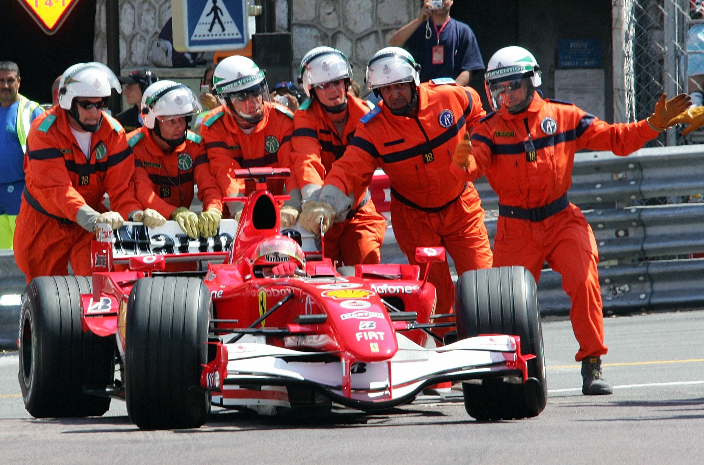 Comisarios de pista de Mónaco empujan el Ferrari de Schumacher tras quedarse parado en la pista durante la clasificación de 2006.