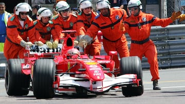 Comisarios de pista de Mónaco empujan el Ferrari de Schumacher tras quedarse parado en la pista durante la clasificación de 2006.