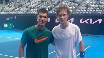 Alcaraz y Rublev se abrazan al acabar un entrenamiento en Melbourne Park.