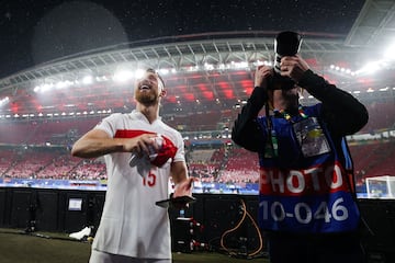 El centrocampista turco Salih Ozcan celebra el pase a cuartos tras ganar a Austria mientras un reportero gráfico fotografía al público.