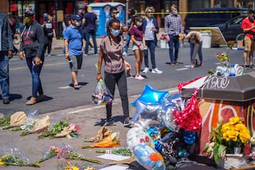 A woman brings flowers to a memorial for George Floyd, who died while in custody of the Minneapolis police, following a day of demonstration in a call for justice on May 30, 2020 in Minneapolis, Minnesota. - Demonstrations are being held across the US after George Floyd died in police custody on May 25. (Photo by kerem yucel / AFP)