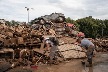 Dos personas realizan labores de limpieza al lado de una montaña de basura, vehículos y mobiliario destrozado tras el paso de la DANA en Alfafar, a 9 de noviembre de 2024, en Alfafar, Valencia, Comunidad Valenciana (España).