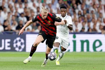 Haaland y Vinicius pelean por un balón.