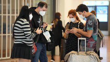 Passengers look at smartphones at the arrival lobby of Haneda Airport in Tokyo, Japan, on Tuesday, Oct. 11, 2022. Japan began accepting vaccinated visitors from 68 countries without visas Tuesday, ending almost three years of tighter border controls that kept tourists out of the island nation. Photographer: Toru Hanai/Bloomberg via Getty Images