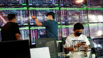 People pass their time at a cafe which has dozens of screens showing the latest trends and prices on various cryptocurrencies for their crypto investors' customers in Nakhon Ratchasima, Thailand.
