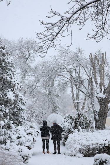 Dos personas caminan por la nieve en Madrid.