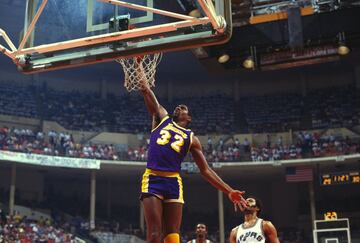 Antes de Michael Jordan, Earving ‘Magic’ Johnson y Larry Bird rescataron a una NBA en decadencia y la pusieron rumbo a su edad de oro. Magic, un base de 2,06 con una visión de juego que parecía cosa de ciencia ficción, lideró a los Lakers del Showtime que ganaron cinco anillos en los años 80 y, sobre todo, crearon un estilo de juego eléctrico e inolvidable y conectaron con la cultura de Hollywood para, desde el viejo Forum de Inglewood, convertir a los Lakers en un emblema global del deporte. Uno de los jugadores con más carisma que jamás ha pisado una cancha de baloncesto, ya era sensación en Michigan State cuando jugó (y ganó) en 1979 la final universitaria más mediática de la historia contra la Indiana State de, cómo no, Larry Bird. Promedió 11,2 asistencias en una carrera truncada en su última fase por el VIH contra el que luego hizo una campaña de concienciación que los expertos consideraron clave para romper tabús en la sociedad estadounidense. Ahora un empresario de enorme éxito, el apodo de ‘Magic’ nació cuando todavía jugaba en instituto y se lo puso el periodista Fred Stabley, del ‘Lansing State Journal’: "Necesitas un apodo y si te parece bien, te voy a llamar Magic". Acababa de firmar 36 puntos, 18 rebotes y 16 asistencias.