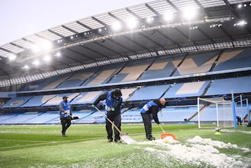 Operarios del Manchester City retiran el hielo del campo tras una granizada.