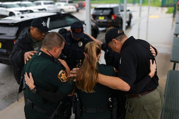 Miembros de la Oficina del Sheriff del Condado de Polk rezan afuera de un refugio mientras se acerca el huracán Milton, en Lakeland, Florida