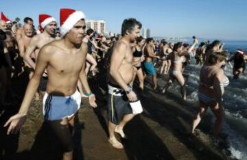 Decenas de ciudadanos participaron este mediodía en el tradicional primer baño del año en la playa de Sant Sebastià del barcelonés barrio de la Barceloneta.