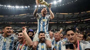 LUSAIL CITY, QATAR - DECEMBER 18: Lionel Messi of Argentina celebrates with the FIFA World Cup Qatar 2022 Winner's Trophy on Sergio 'Kun' Aguero's shoulders after the team's victory during the FIFA World Cup Qatar 2022 Final match between Argentina and France at Lusail Stadium on December 18, 2022 in Lusail City, Qatar. (Photo by David Ramos - FIFA/FIFA via Getty Images)