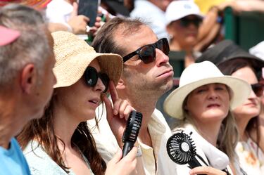 Los espectadores se refrescan con abanicos durante el segundo día del Campeonato de Wimbledon 2025.