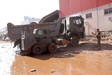 Un soldado junto a una excavadora y un camión militares en un polígono industrial en una zona afectada por las inundaciones en Chiva,