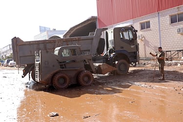 Un soldado junto a una excavadora y un camión militares en un polígono industrial en una zona afectada por las inundaciones en Chiva,