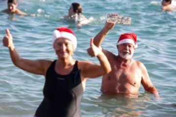 Decenas de ciudadanos participaron este mediodía en el tradicional primer baño del año en la playa de Sant Sebastià del barcelonés barrio de la Barceloneta.