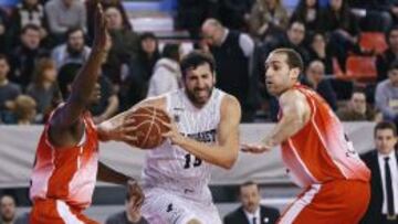  El alero del Bilbao Basket, &Aacute;lex Mumbr&uacute; intenta avanzar con el bal&oacute;n ante los jugadores de La Bruixa D&#039;or, Max Kouguere y Oliver Artega.