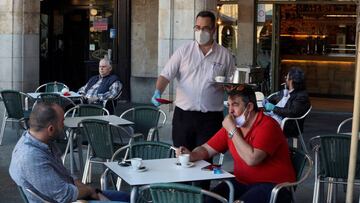 Un camarero sirve a los clientes en su bar de la Plaza Mayor de Salamanca durante el primer d&iacute;a de la fase 1 en la ciudad.