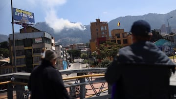 People watch smoke rising from a forest fire on a hill, after the district government declared an air quality emergency, in Bogota, Colombia, January 26, 2024. REUTERS/Luisa Gonzalez