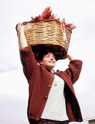 Carmen Sevilla con una cesta de marisco en la cabeza en su casa de San Juan, Alicante.
