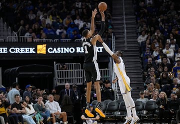 Victor Wembanyama, de los San Antonio Spurs, lanza delante del jugador de los Golden State Warriors, Jonathan Kuminga.